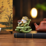 Tea pet rana dorata in resina su poltrona a dondolo